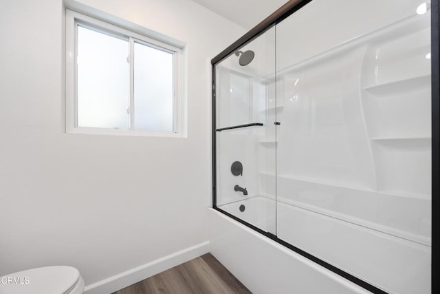 bathroom featuring hardwood / wood-style flooring, bath / shower combo with glass door, and toilet