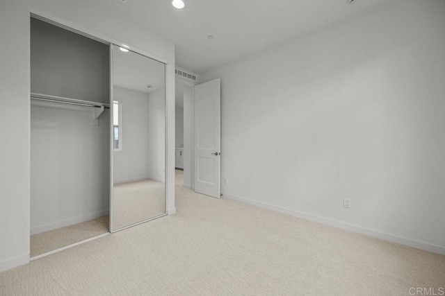 unfurnished bedroom with a closet, visible vents, recessed lighting, carpet floors, and baseboards