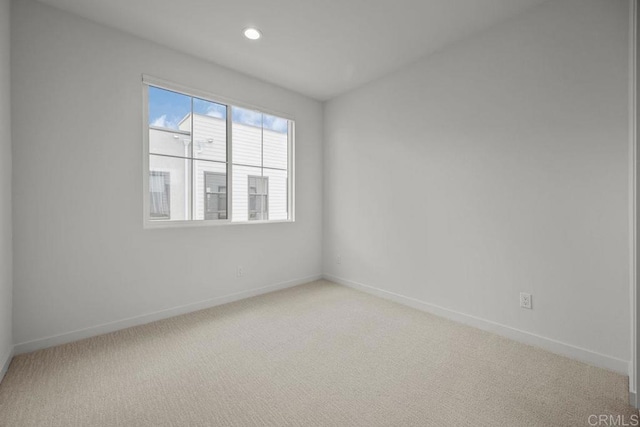 empty room featuring baseboards, recessed lighting, and light carpet
