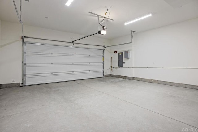 garage featuring a garage door opener, baseboards, and electric panel