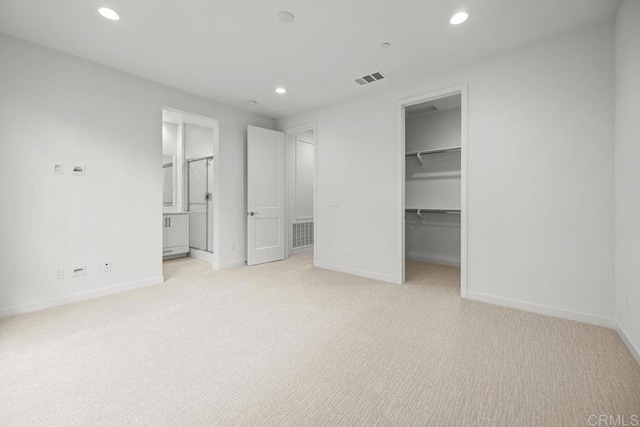 unfurnished bedroom with baseboards, a closet, a spacious closet, recessed lighting, and light colored carpet
