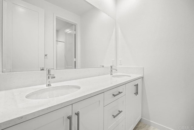 bathroom with a sink, baseboards, and double vanity