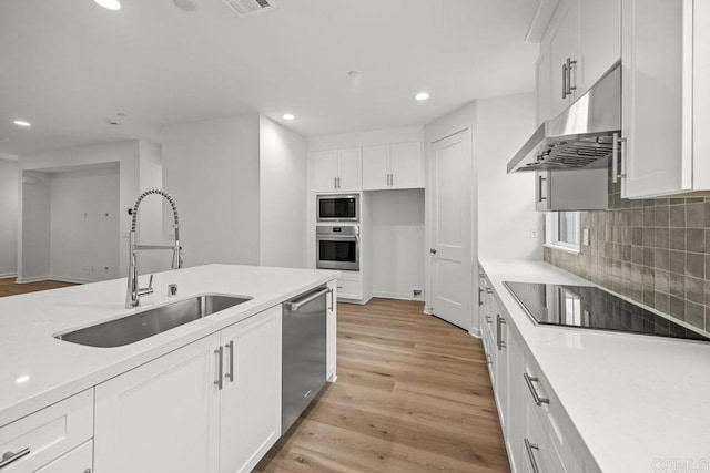 kitchen featuring a sink, light wood-type flooring, under cabinet range hood, recessed lighting, and stainless steel appliances