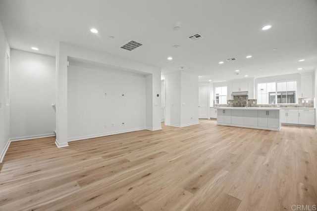 unfurnished living room with light wood-style floors, recessed lighting, and visible vents