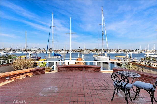 view of patio with a water view and a dock