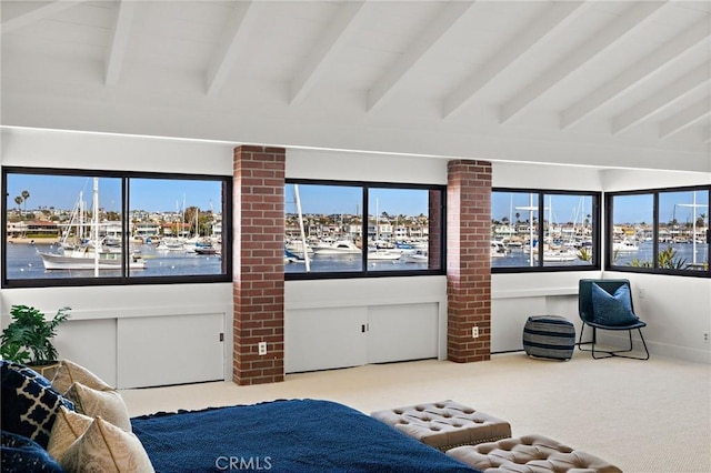 bedroom with a water view, light colored carpet, and beam ceiling