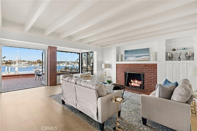 living room with a water view, a fireplace, hardwood / wood-style flooring, built in features, and beam ceiling