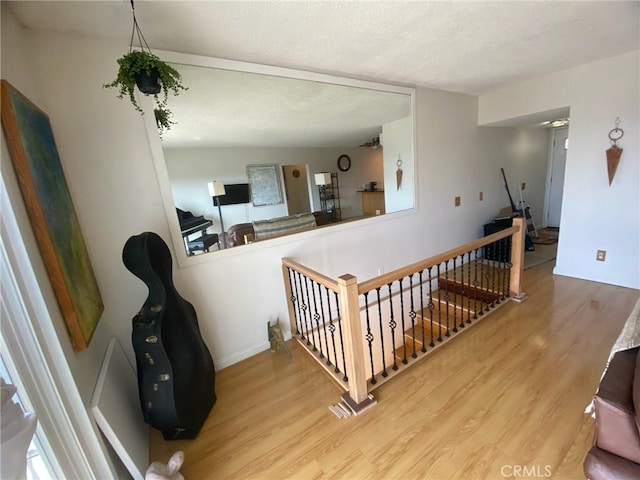 stairway with a textured ceiling, baseboards, and wood finished floors