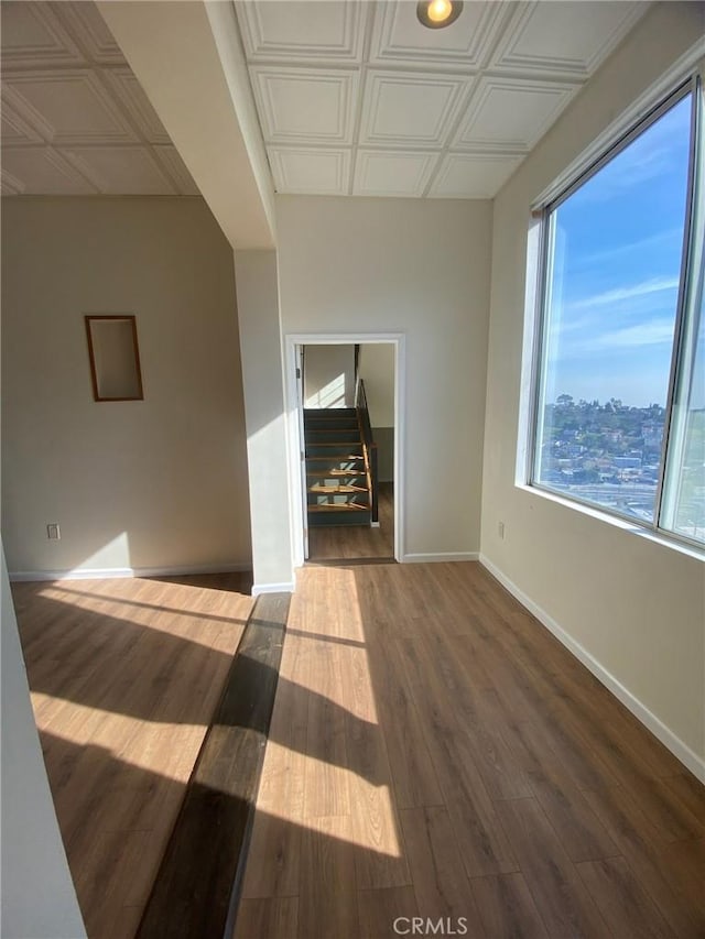 unfurnished room with an ornate ceiling, baseboards, and wood finished floors
