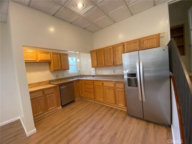 kitchen with light wood-style floors, a sink, appliances with stainless steel finishes, and brown cabinets