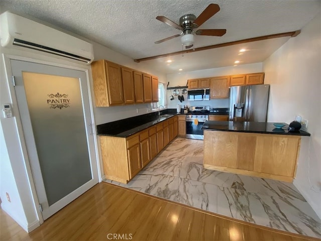 kitchen with dark countertops, appliances with stainless steel finishes, a sink, an AC wall unit, and a textured ceiling