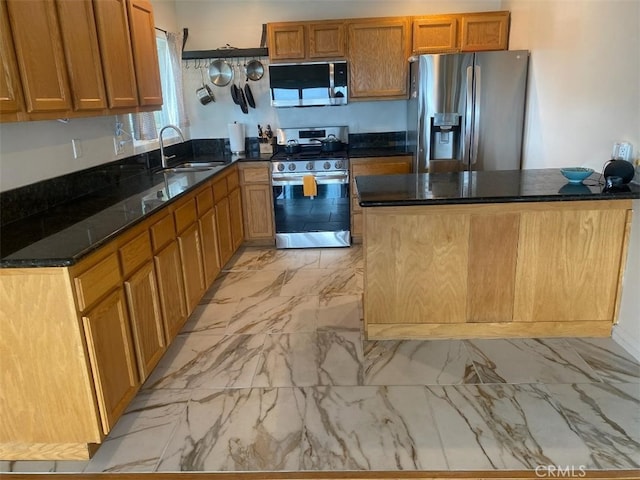 kitchen with brown cabinets, a sink, marble finish floor, dark stone counters, and stainless steel appliances