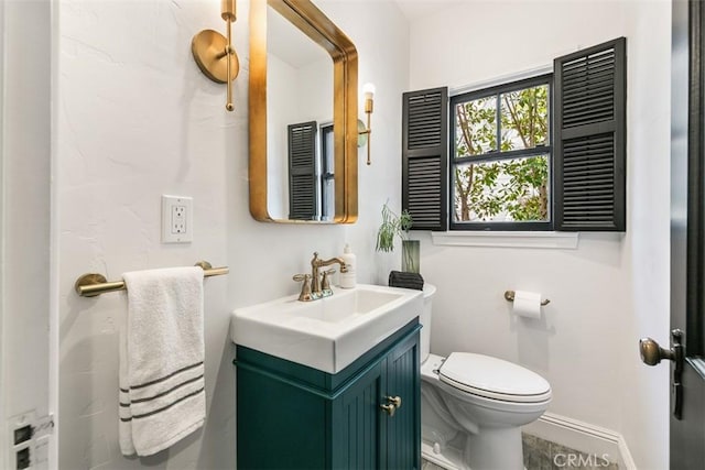 bathroom featuring toilet, baseboards, and vanity