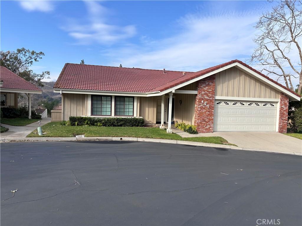 single story home with concrete driveway, a tiled roof, and a garage