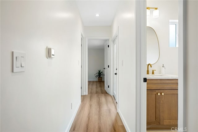 hallway featuring light wood-style floors and baseboards