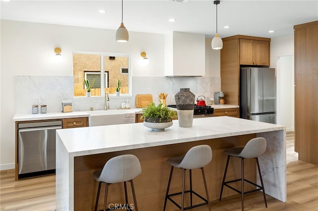 kitchen featuring stainless steel appliances, light wood-style floors, a sink, and decorative backsplash