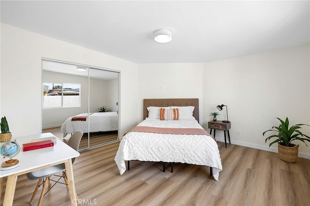 bedroom featuring light wood finished floors, baseboards, and a closet