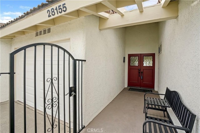 entrance to property featuring a gate, visible vents, and stucco siding