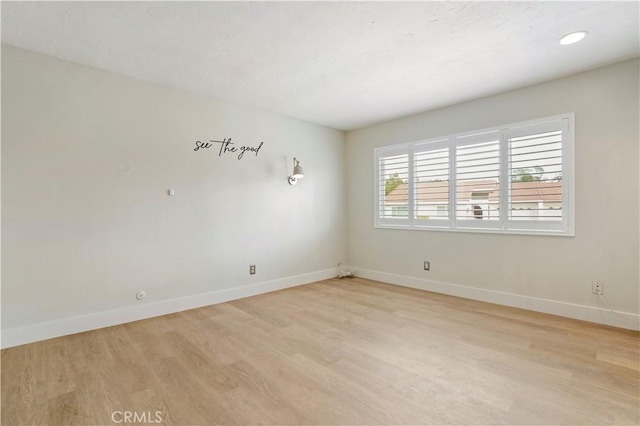 spare room featuring light wood finished floors and baseboards