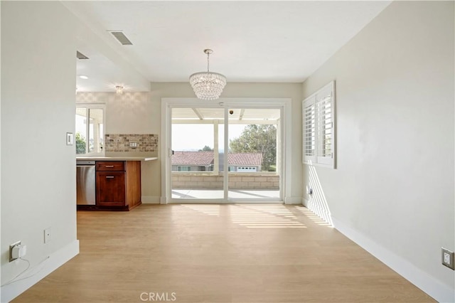 unfurnished dining area with visible vents, light wood-style flooring, a chandelier, and a wealth of natural light