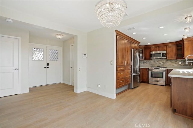 kitchen featuring visible vents, light countertops, appliances with stainless steel finishes, light wood finished floors, and glass insert cabinets