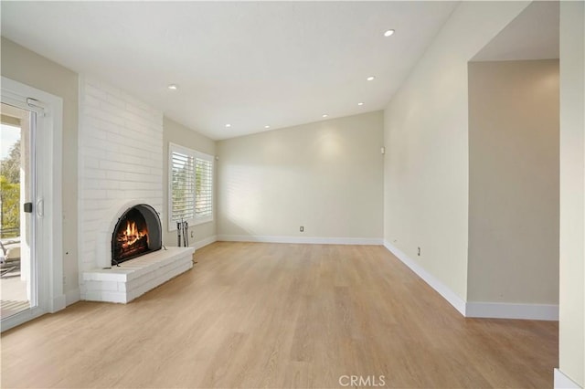 unfurnished living room with light wood-style floors, recessed lighting, a fireplace, and baseboards