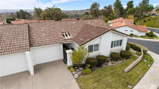 view of front of property featuring driveway, an attached garage, a tile roof, and a front yard