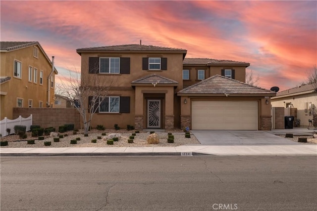 view of front of house with a garage, concrete driveway, fence, and stucco siding