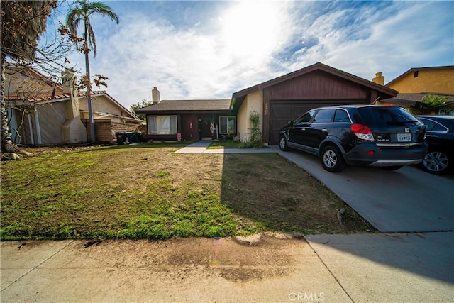 single story home with a front yard, concrete driveway, and an attached garage