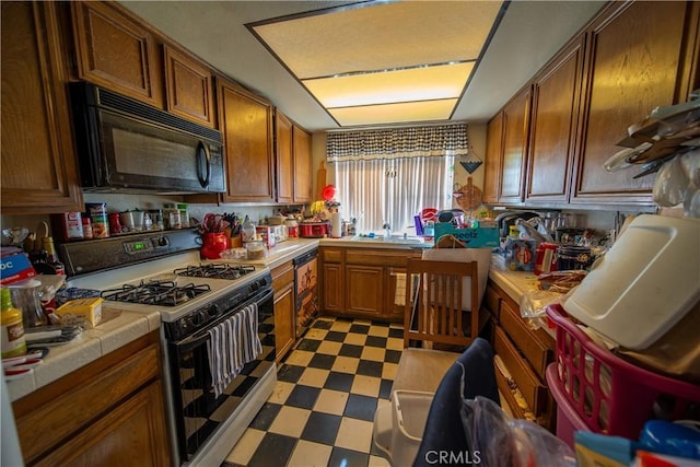 kitchen with white gas range oven, tile countertops, dark floors, brown cabinets, and black microwave