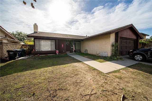 ranch-style home with a garage, concrete driveway, a front lawn, and stucco siding