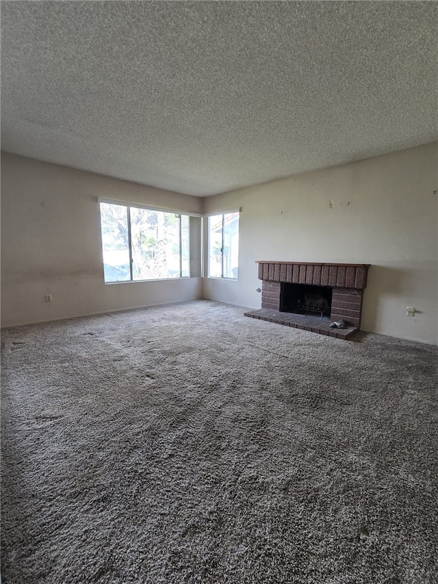 unfurnished living room with carpet, a brick fireplace, and a textured ceiling