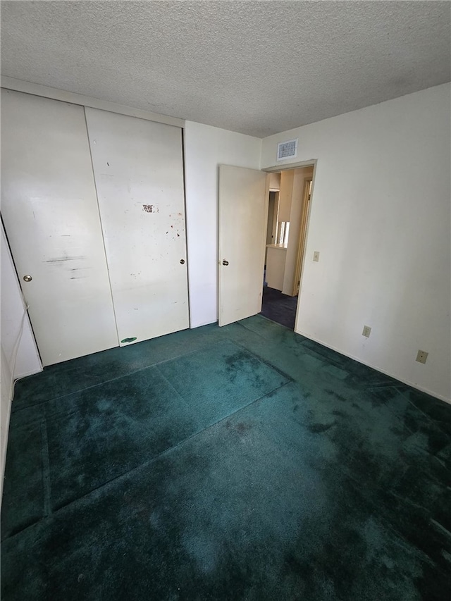 unfurnished bedroom with carpet, visible vents, a closet, and a textured ceiling