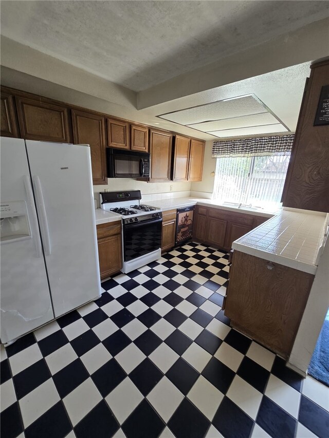 kitchen with white fridge with ice dispenser, black microwave, tile countertops, light floors, and gas range oven
