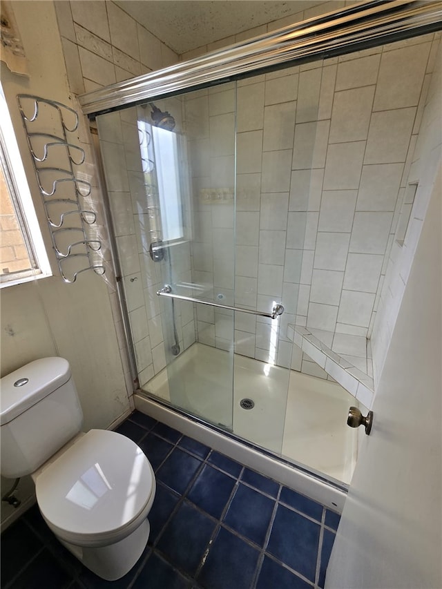 full bath featuring toilet, tile patterned flooring, and a stall shower