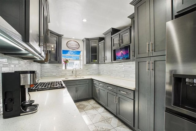 kitchen with sink, appliances with stainless steel finishes, light stone countertops, and decorative backsplash