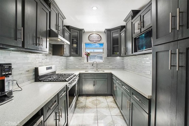 kitchen featuring sink, stainless steel range with gas stovetop, light stone countertops, and tasteful backsplash