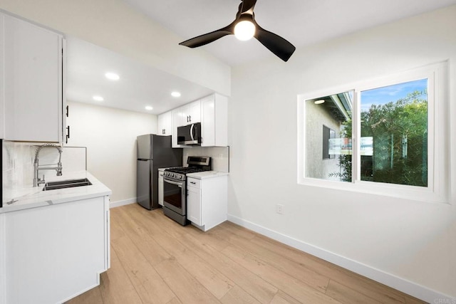 kitchen featuring light wood-type flooring, stainless steel appliances, decorative backsplash, sink, and white cabinetry