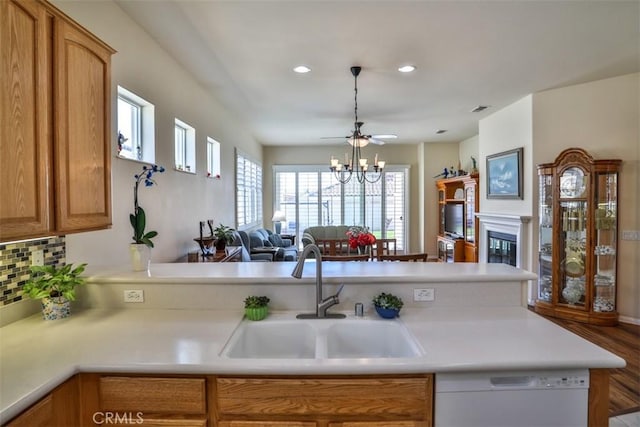 kitchen with a glass covered fireplace, light countertops, white dishwasher, and a sink