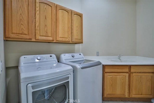 clothes washing area featuring separate washer and dryer, a sink, and cabinet space