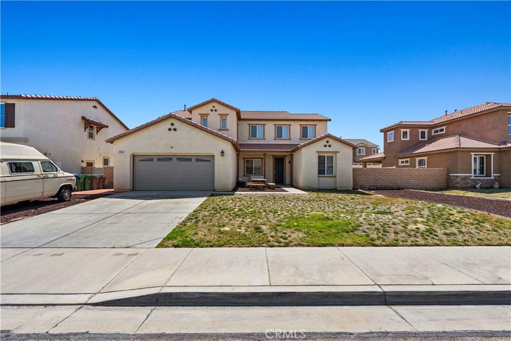 view of front of home with driveway, stucco siding, fence, and an attached garage