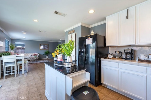 kitchen featuring tile counters, white cabinets, decorative backsplash, and black fridge