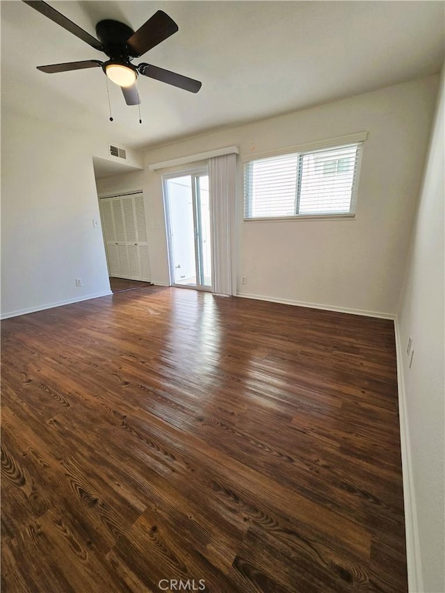 spare room with visible vents, dark wood finished floors, baseboards, and ceiling fan