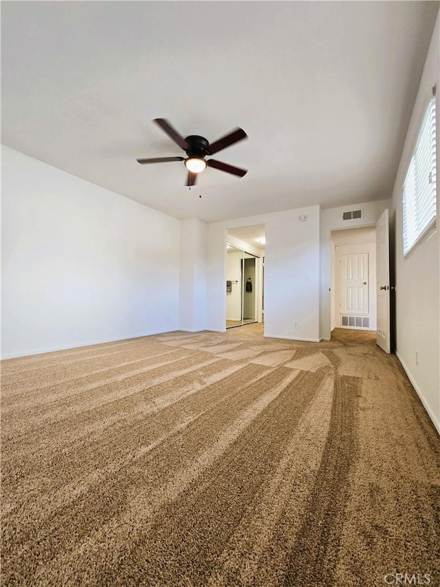 carpeted empty room with visible vents and a ceiling fan