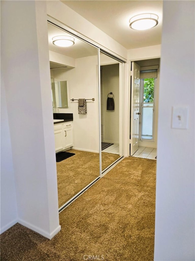 hall with baseboards and light colored carpet