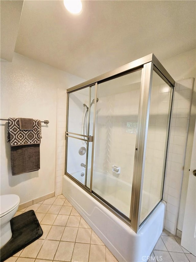 bathroom with bath / shower combo with glass door, toilet, and tile patterned floors