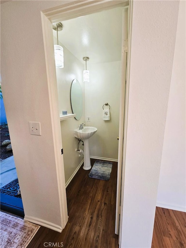 half bathroom featuring a sink, baseboards, and wood finished floors