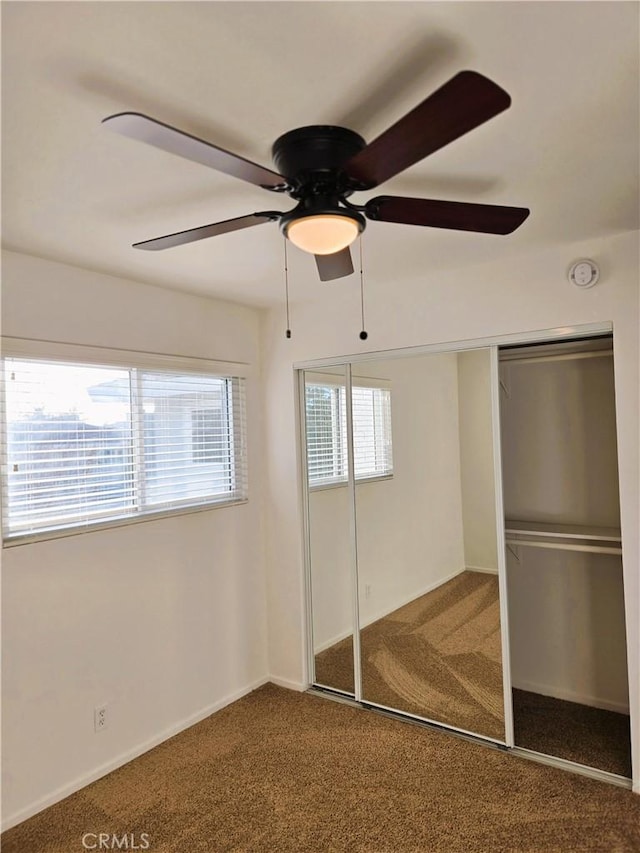 unfurnished bedroom featuring a ceiling fan, a closet, and carpet flooring