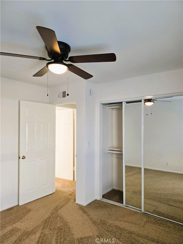 unfurnished bedroom with ceiling fan, a closet, visible vents, and carpet flooring