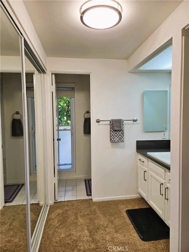 bathroom with vanity, baseboards, and tile patterned floors